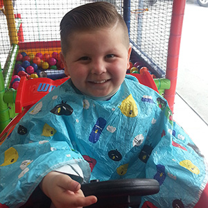 Niño disfrutando de un corte de cabello en Kota Pelo
